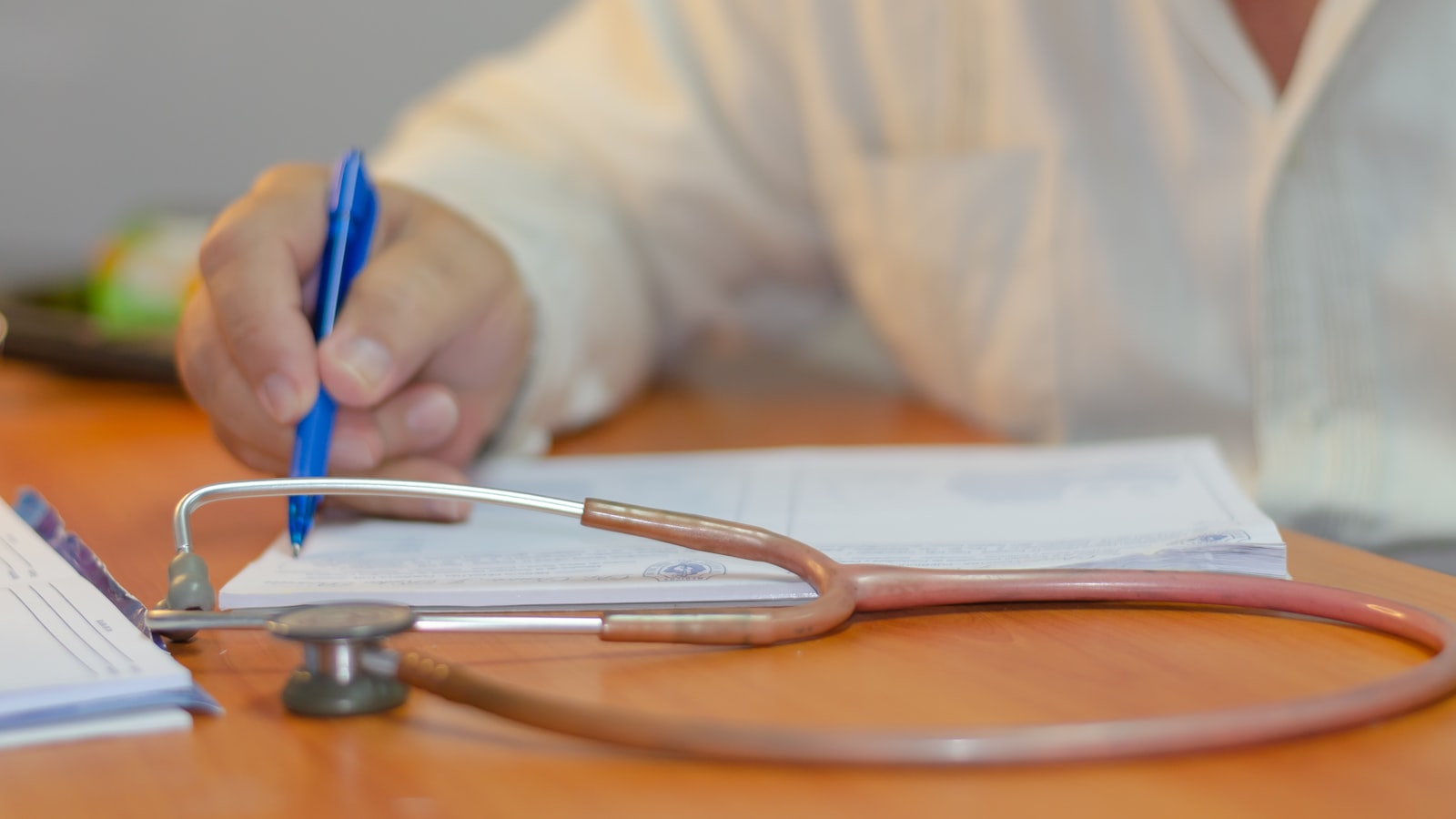 a person writing on a piece of paper with a stethoscope